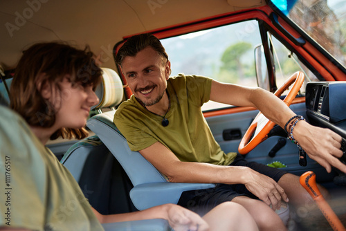 Smiling man teaching his teenage son how to drive caravan photo