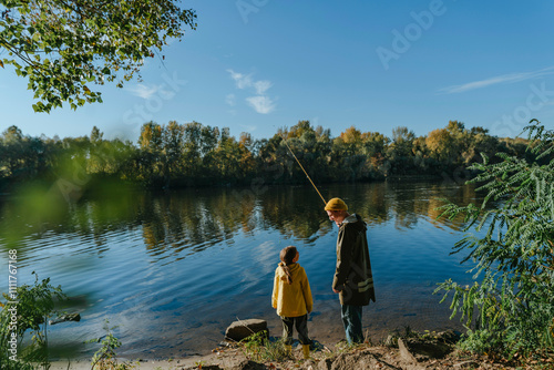 Father and daughter fishing in river on sunny day photo