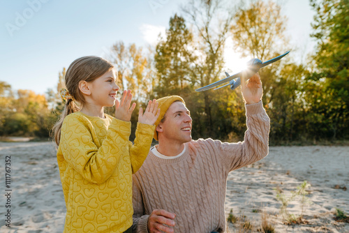 Happy daughter and father playing with toy airplane on sunny day0 photo