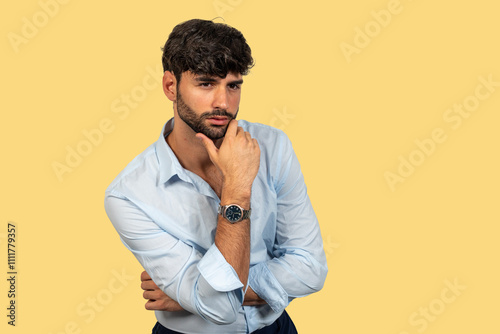 Pensive businessman with hand on chin looking away on yellow background