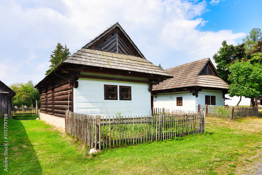 Rare wooden bell tower with folk houses in background. These preserved constructions are located in open-air museum of Liptov Village, Slovakia - Pribylinaopen-air museum of Liptov Village, Slovakia. Rare wooden bell tower with folk houses in background. These preserved constructions are located in open-air museum of Liptov Village, Slovakia - Pribylinaopen-air museum of Liptov Village, Slovakia.