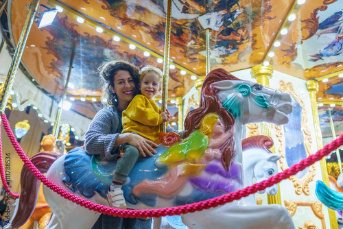 Mother and son enjoying carousel ride at amusement park photo