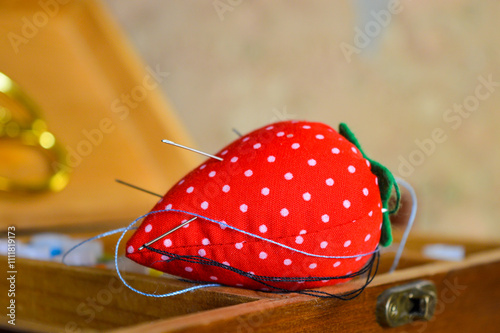 bright red pincushion shaped like a strawberry сraft tutorials sewing and DIY kits related tools creativity hobbies work educational basics beginner hands-on crafting atmosphere needles and threads photo