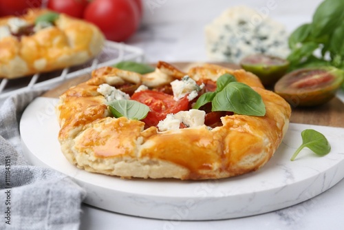 Tasty galette with tomato, basil and cheese on white marble table, closeup