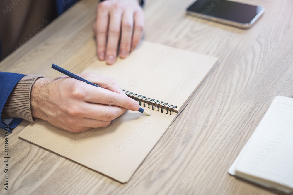 Φωτογραφία A man's hand is caught in close-up, busily writing in a notepad, while the backg