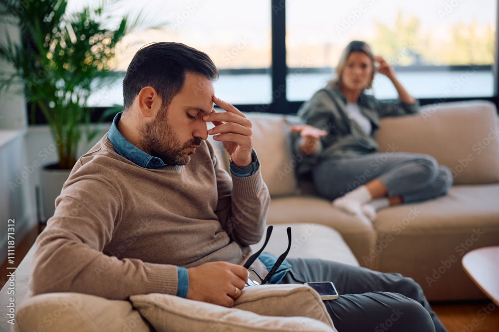 Stressed man having headache while arguing with his wife at home. Stressed man having headache while arguing with his wife at home.