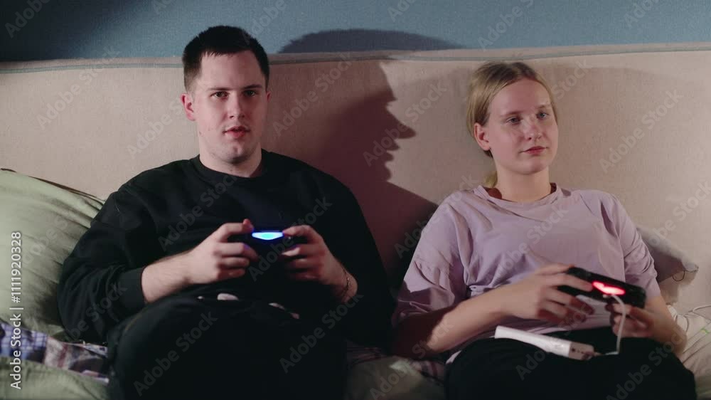A teenage girl and her older brother sitting on a bed, engrossed in playing video games together, holding controllers and enjoying a relaxed family moment. A teenage girl and her older brother sitting on a bed, engrossed in playing video games together, holding controllers and enjoying a relaxed family moment.