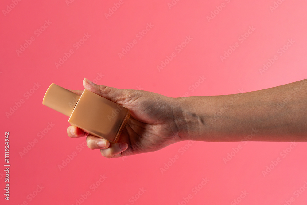 Fototapeta premium Cosmetic cream tube in womans hand on pink background 