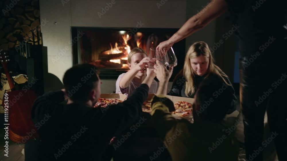A group of young people eating pizza near a glowing fireplace as a woman serves drinks, accompanied by a playful dog, enjoying a cheerful pre-holiday mood in a cozy home. A group of young people eating pizza near a glowing fireplace as a woman serves drinks, accompanied by a playful dog, enjoying a cheerful pre-holiday mood in a cozy home.