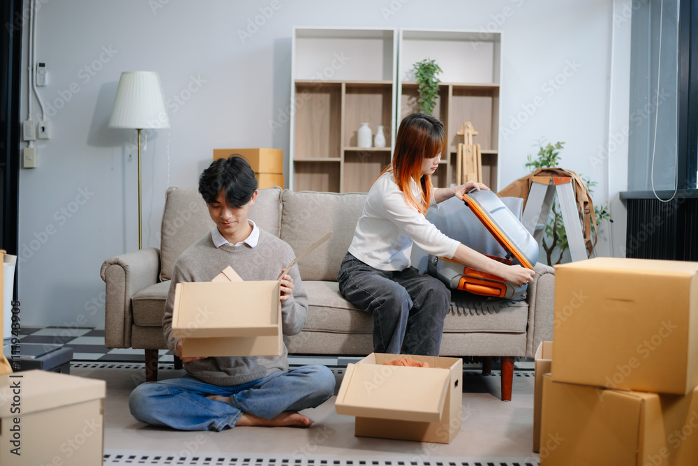 Young couple preparing for a move, packing boxes and a suitcase in a cozy living room. Perfect for themes of relocation Young couple preparing for a move, packing boxes and a suitcase in a cozy living room. Perfect for themes of relocation
