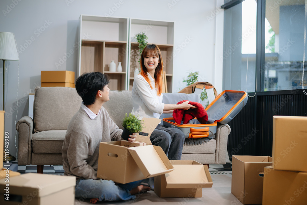 Young couple preparing for a move, packing boxes and a suitcase in a cozy living room. Perfect for themes of relocation Young couple preparing for a move, packing boxes and a suitcase in a cozy living room. Perfect for themes of relocation