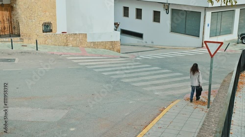 Person waiting to cross a quiet urban street at a crosswalk