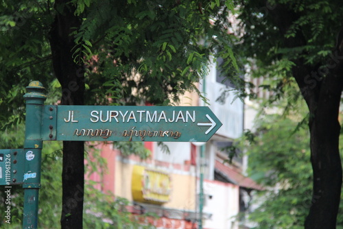 Directional signpost in Indonesian and Javanese script with a blurred  background, symbolizing cultural heritage, navigation, and travel