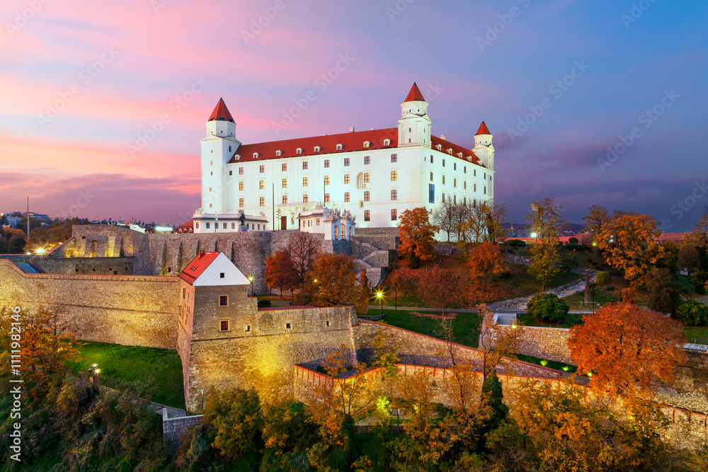 Fototapeta premium Aerial view of the beautifully illuminated Bratislava Castle after an autumn sunset