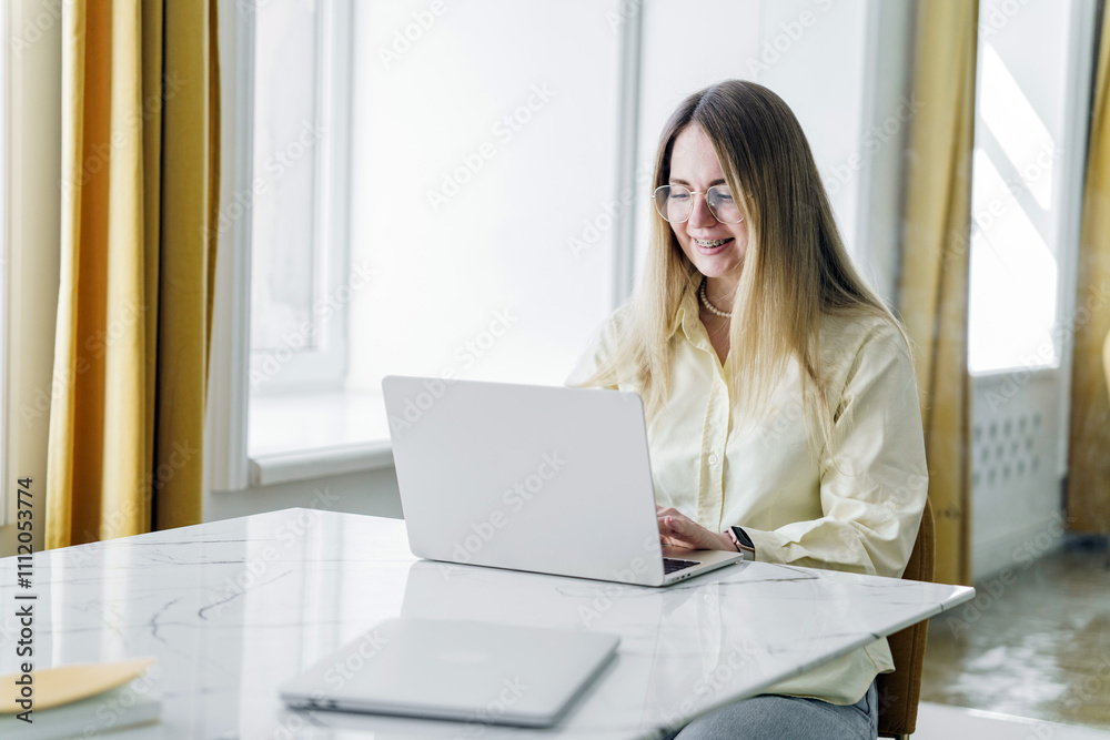 Woman working on laptop at a bright indoor workspace with cheerful atmosphere in the afternoon Woman working on laptop at a bright indoor workspace with cheerful atmosphere in the afternoon