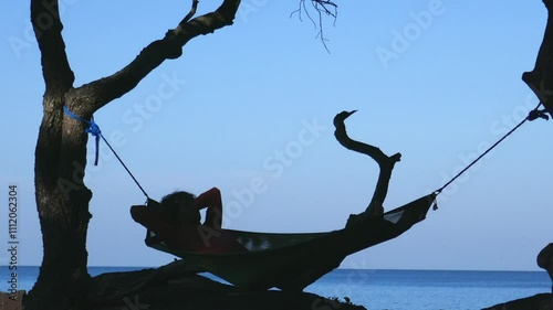 a man rests in a hammock on the seashore in the tropics