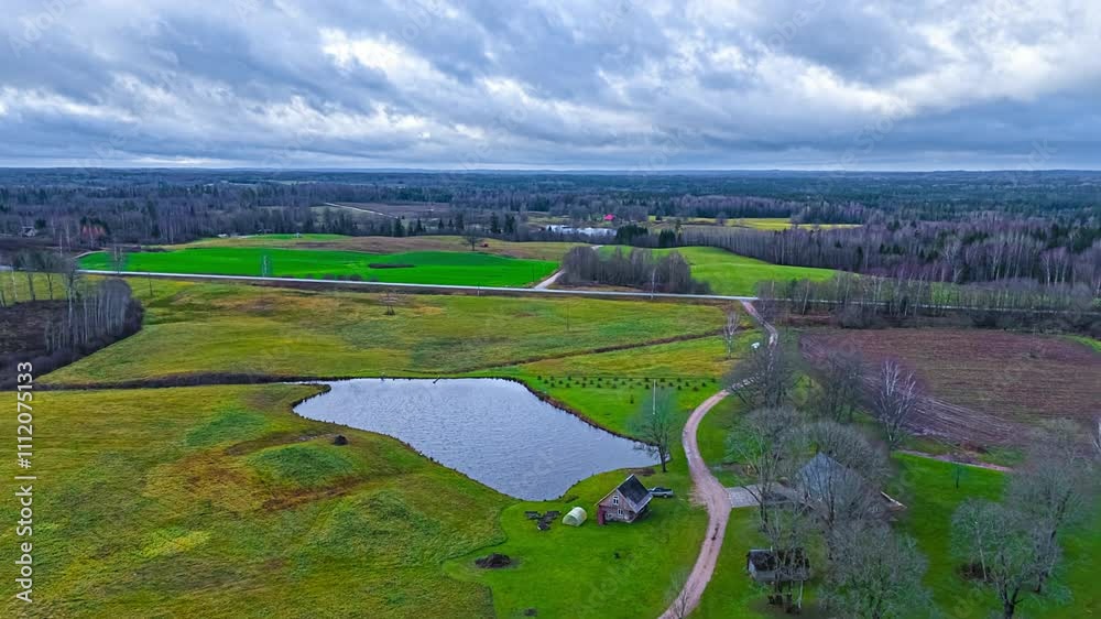 Pond and farmland fields in autumn - aerial parallax hyper lapse on a stormy day with dramatic cloudscape
