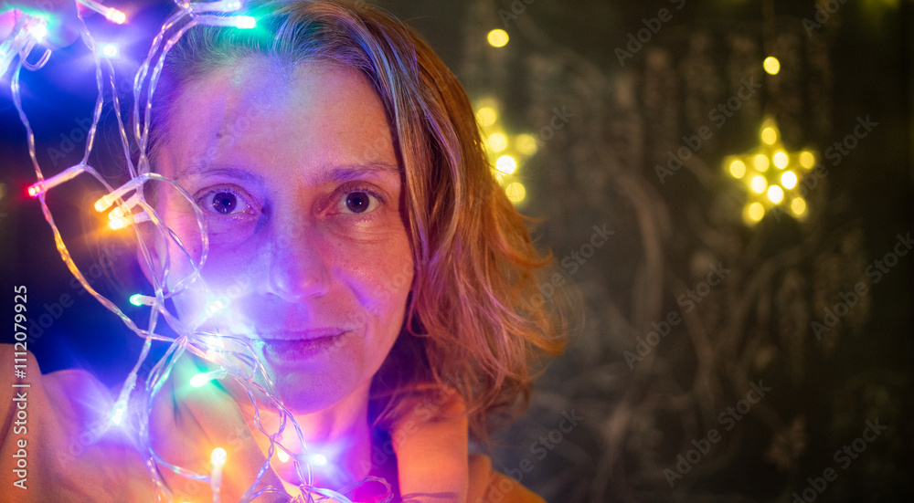 Naklejka premium woman hanging up colorful Christmas lights