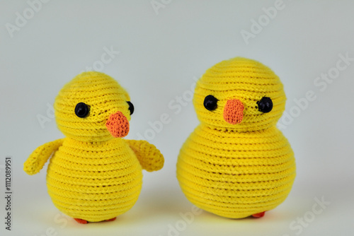 Two yellow crocheted ducks. A knitted duck with a gray background. Knitted duck gray background yellow toy. A duck toy with a gray background and yellow lifestyle toy. photo