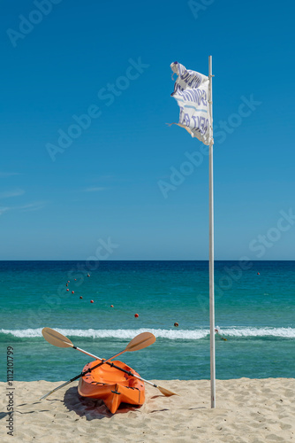 An orange kayak with two paddles on the sandy beach of Cala Sinzias, Sardinia, Italy photo