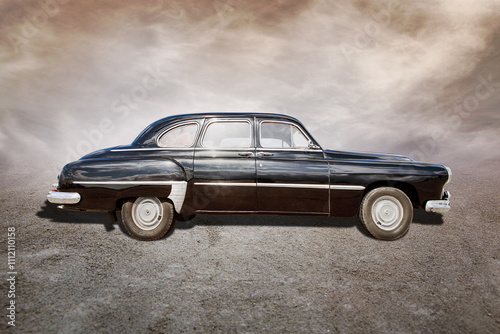 old car stands on sepia clouds background