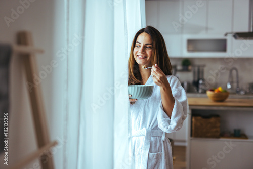 Smiling Woman Enjoying Breakfast In Cozy Kitchen Wearing White Robe