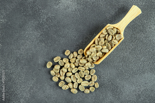 A wooden spoon filled with green coffee beans, top view