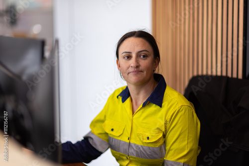 adult woman in high visibility clothes working in front of her computer in an office. photo