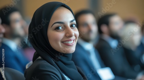 Diverse group of professionals attending a business conference with a Muslim woman smiling in the audience