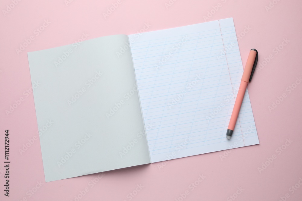 Open copybook and pen on pink background, top view. School stationery Open copybook and pen on pink background, top view. School stationery
