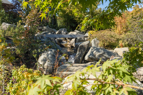 Krasnodarsky Japanese Garden. Picturesque artificial waterfall built from huge natural stones. Water falls into artificial rock bed. Banks are fortified with huge natural stones and boulders. photo