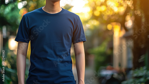 blue T-shirt mockup concept. man wearing blue T shirt stands in sunlit outdoor setting