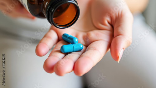 Hand with Capsules Dispensed from Brown Bottle Against Blurred Fabric Background