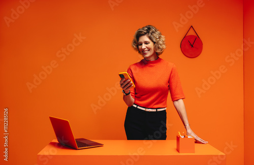 Successful mature woman in monochromatic office set engaging in mobile communication