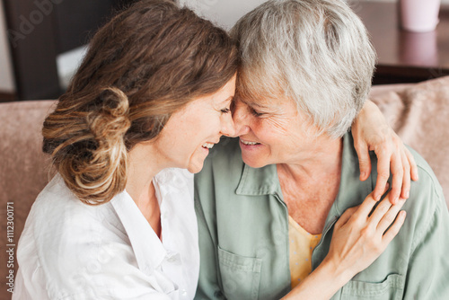 Older mature mother and grown millennial daughter laughing embracing, caring smiling young woman embracing happy senior middle aged mom