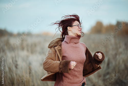 Foto Teen girl smiling with windswept hair, enjoying a cold and breezy day in an open field
