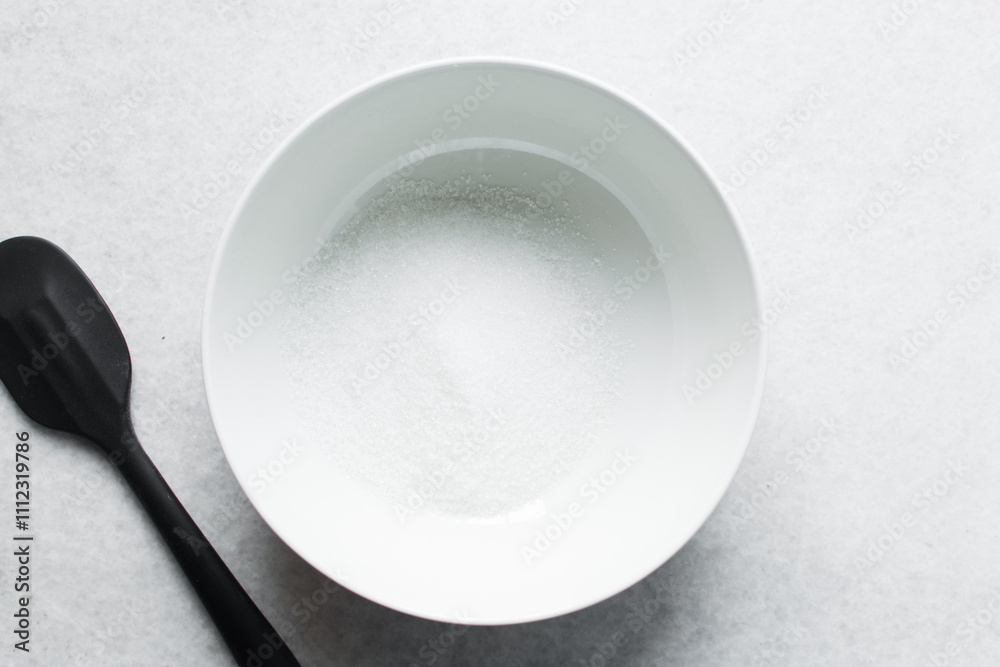 Overhead view of white sugar in a white plate, top view of granulated sugar in a plate Overhead view of white sugar in a white plate, top view of granulated sugar in a plate