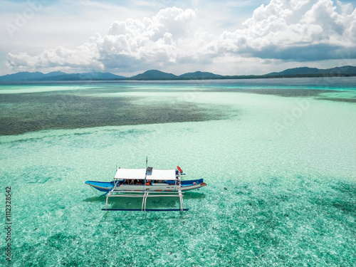 Tableau sur toile An aerial view of a traditional Filipino outrigger boat (bangka) anchored in sha