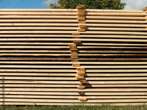 stacking planed boards in a factory or construction site outdoors, planks stacked on top of each other with crossbars, creating a natural texture photo