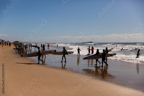 surf lifesaving board race competitors in silhouette on a sunny day
