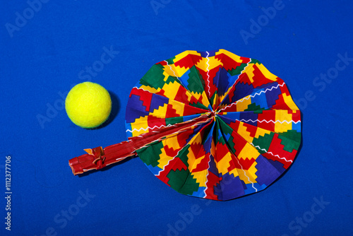 Colorful patterned folding fan near yellow tennis ball photo