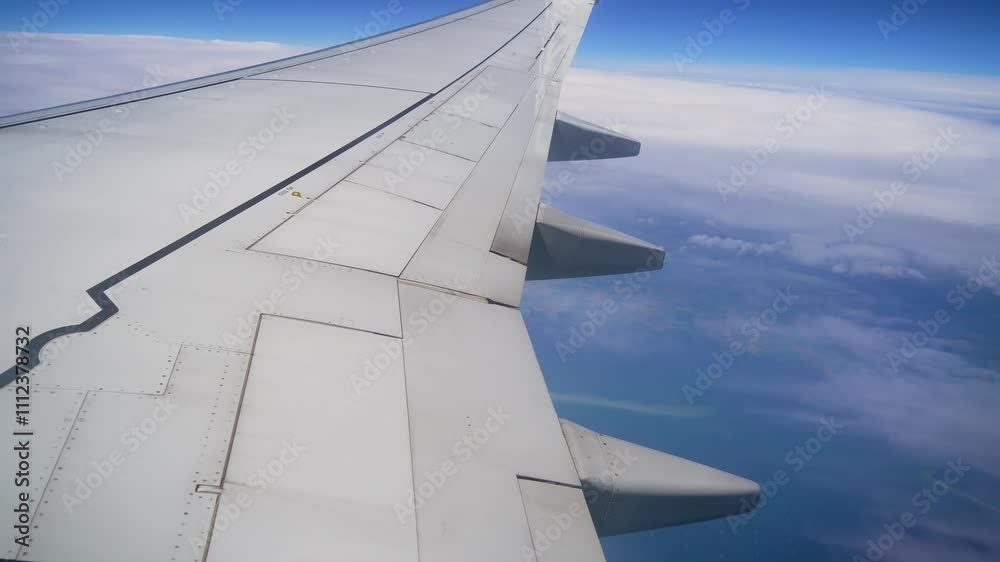 Plane Wing Soaring Above Clouds During Serene Daytime Flight in Clear Blue Sky Over Vast Landscapes Below. View from airplane wing captures expansive clouds beneath bright blue sky Plane Wing Soaring Above Clouds During Serene Daytime Flight in Clear Blue Sky Over Vast Landscapes Below. View from airplane wing captures expansive clouds beneath bright blue sky