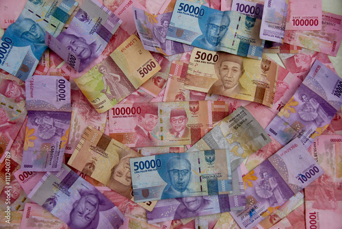 Indonesian rupiah banknotes, five thousand to one hundred thousand rupiah, are randomly positioned photo