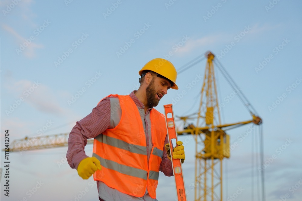 Construction worker wearing safety vest and holding spirit level at construction site Construction worker wearing safety vest and holding spirit level at construction site