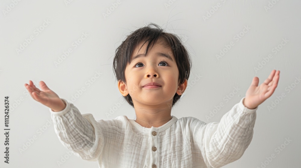 The image depicts a young child with dark hair wearing a white shirt looking up with a smile and Outstretched arms. The image depicts a young child with dark hair wearing a white shirt looking up with a smile and Outstretched arms.