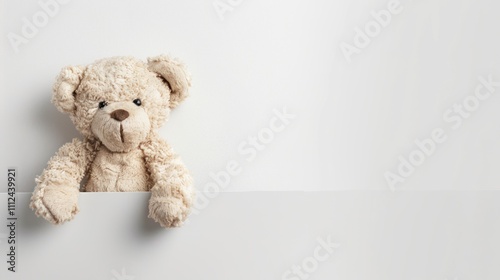 Photo of teddy bear peeking out from the left side on a white background