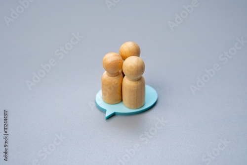 Canvas Print Three wooden figures standing on a blue speech bubble, symbolizing a group consensus or shared opinion