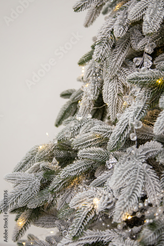 Close-up of a frosted Christmas tree branch decorated with crystal ornaments, pearls, and warm fairy lights, evoking a cozy and elegant holiday atmosphere. Perfect for festive themes and winter decor 