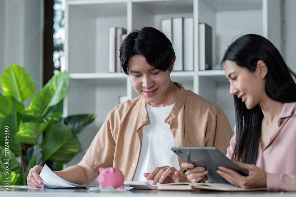 Young Couple Planning Finances Together with Tablet and Piggy Bank for Future Savings and Budgeting in a Modern Home Office Setting Young Couple Planning Finances Together with Tablet and Piggy Bank for Future Savings and Budgeting in a Modern Home Office Setting