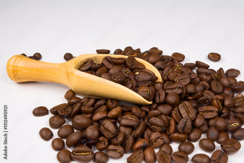Obraz premium Coffee beans with a wooden spoon. A white spoon with coffee beans on a white background. Coffee beans spoon white background brown lies wood. A spoon lying on a wooden background with brown lifestyle.